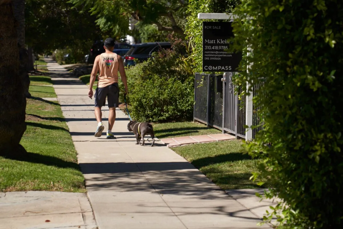 A man walks his dog past a “for sale” sign outside a single-family home in Los Angeles on Sept. 22, 2022. (Allison Dinner/Getty Images)