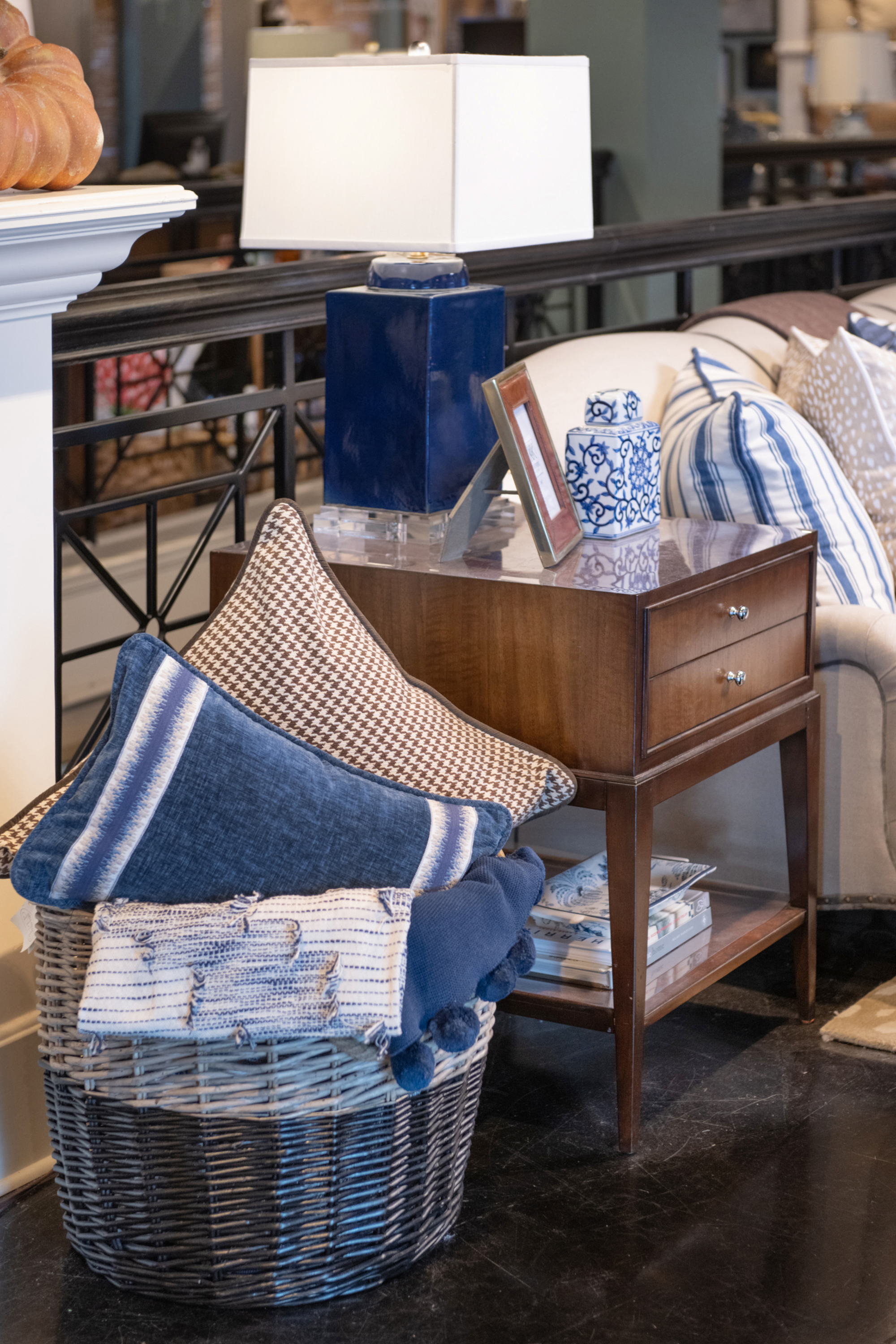 This decorative basket stands out with blue and white pillows and throws featured inside. 