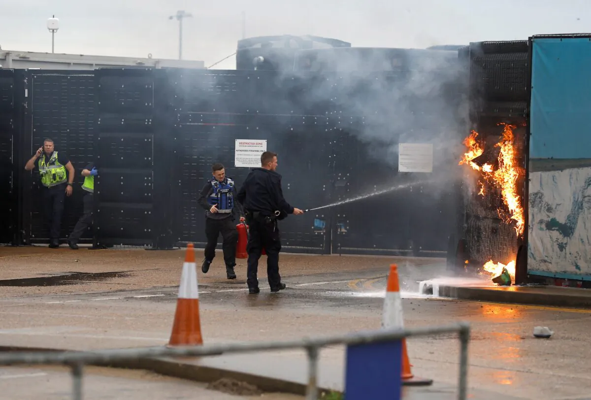 Members of the U.K. military and Border Force extinguish a blaze from a firebomb, targeting a Border Force center in Dover, England, on Oct. 30, 2022. (Peter Nicholls/Reuters)