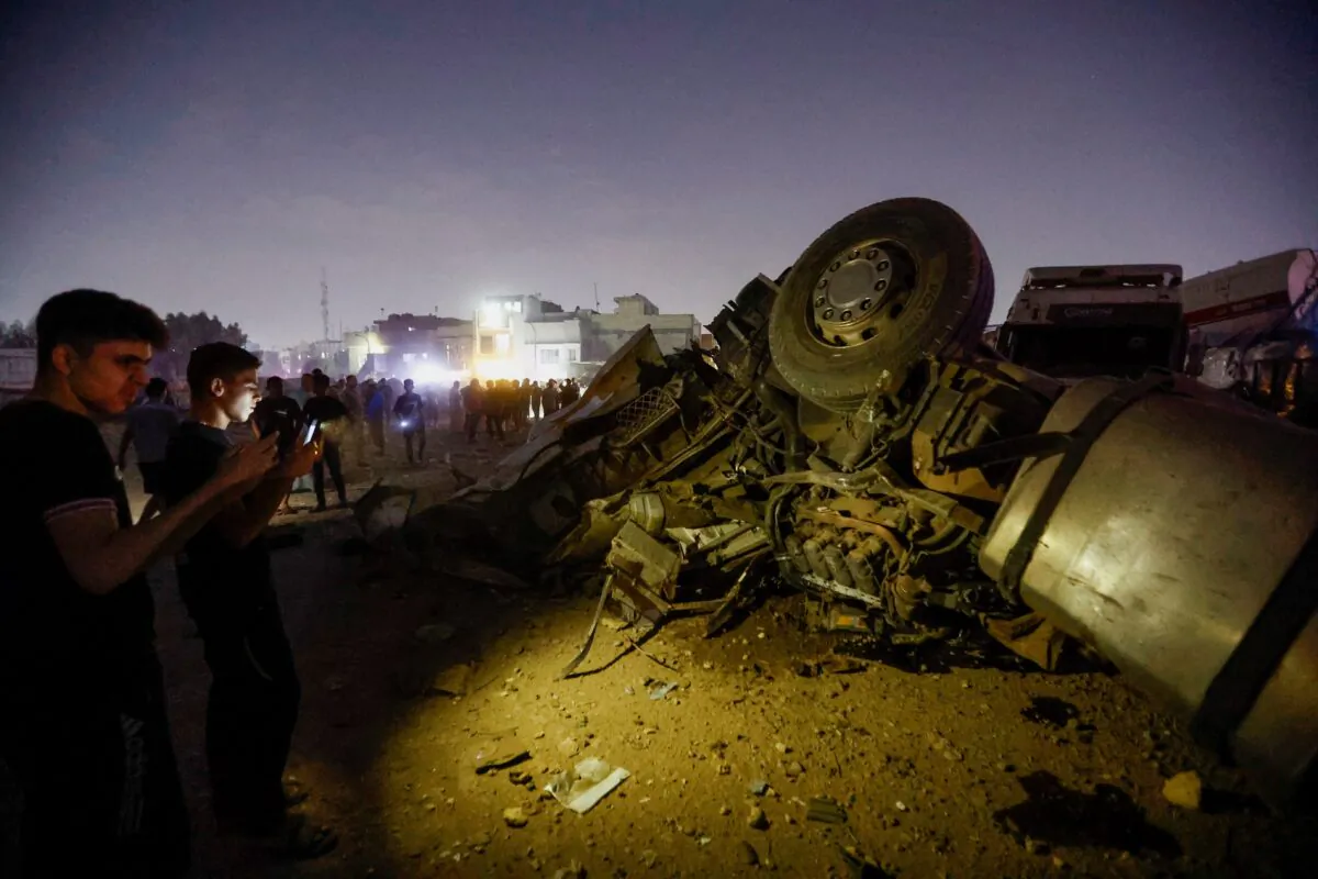Iraqi people inspect the site where an explosive device attached to a vehicle detonated, leading to another explosion of a gas tanker that was close by, in Baghdad, Iraq, on Oct. 29, 2022. (Thaier Al-Sudani/Reuters)