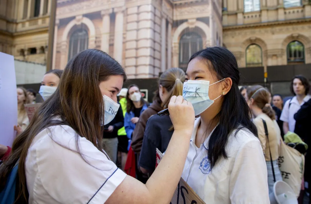 School students write slogans on their masks during a School Strike 4 Climate protest at Sydney Town Hall in Sydney, Australia, on May 6, 2022. (AAP Image/Nikki Short)
