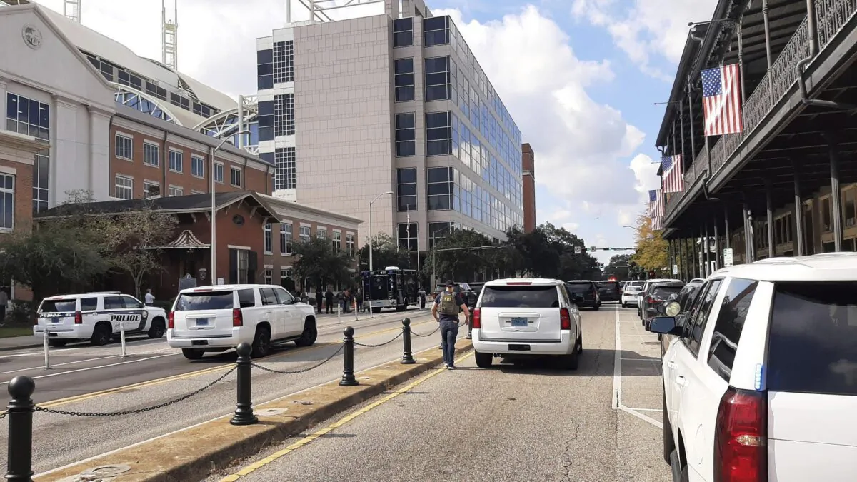 Police officers work on the scene near a parked car with a man inside it suffering from an apparent gunshot wound in downtown Mobile, Ala., on Oct. 31, 2022. (Lawrence Specker/Press-Register via AP)