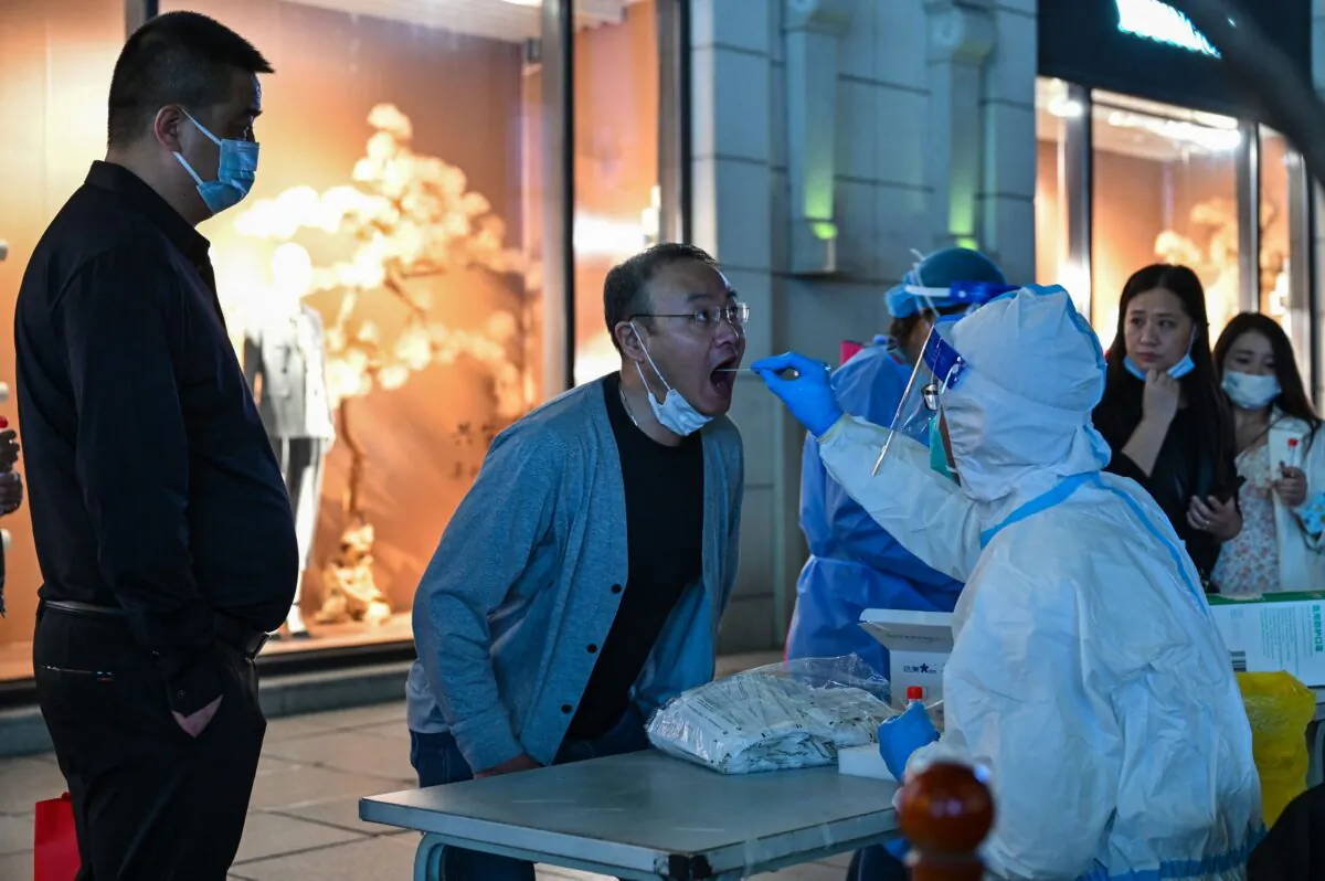 A health worker takes a swab sample from a man to test for the COVID-19 coronavirus in the Huangpu district in Shanghai on Oct. 24, 2022. (Hector Retamal/AFP via Getty Images)