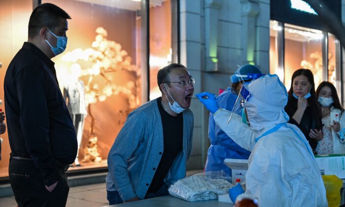2022 年 10 月 24 日，一名卫生工作者在上海黄浦区从一名男子身上采集拭子样本以检测 COVID-19 冠状病毒。（Hector Retamal/AFP via Getty Images）