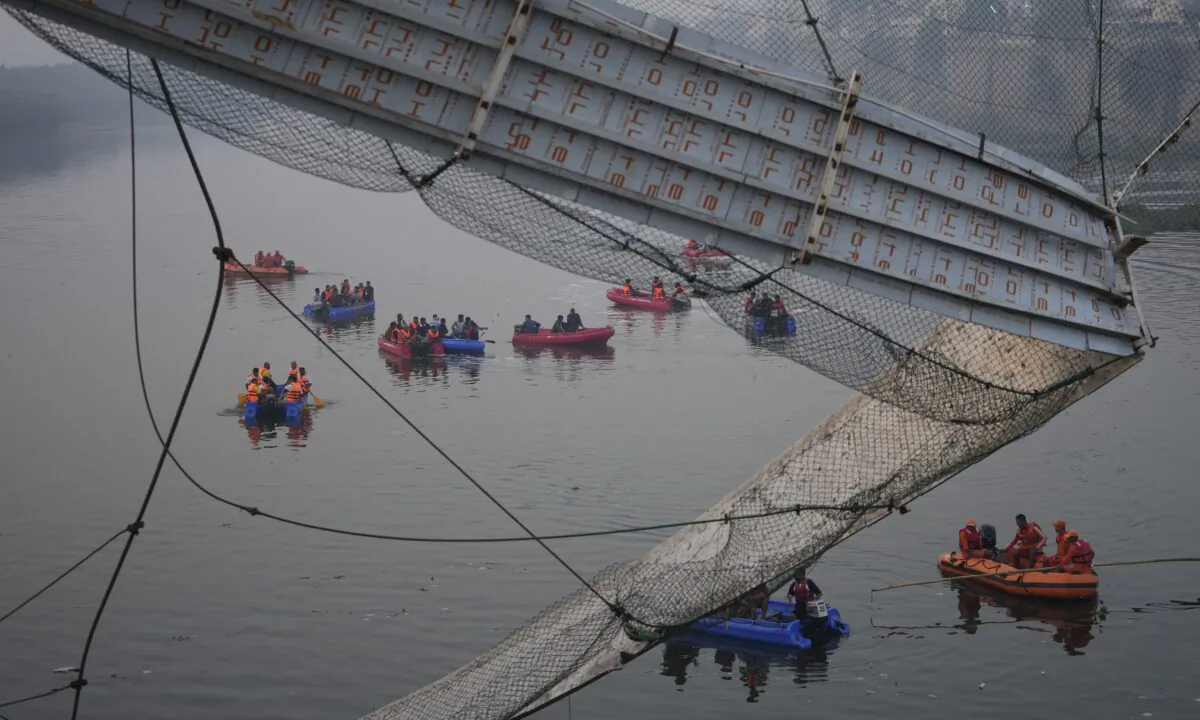 Rescuers on boats search in the Machchu river next to a cable suspension bridge that collapsed in Morbi town of western state Gujarat, India, on Oct. 31, 2022. (Ajit Solanki/AP Photo)