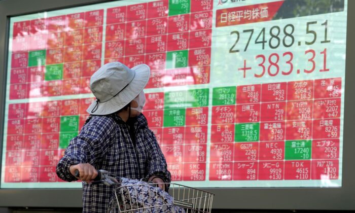 2022 年 10 月 31 日，一名戴着防护口罩的人在东京一家证券公司查看显示日本日经 225 指数的电子股票板。（Eugene Hoshiko/美联社照片）