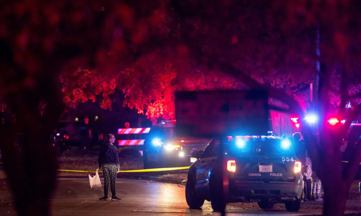 A woman walks by police tape after Omaha police shot a man who drove through a barricaded area during a neighborhood Halloween celebration in Omaha, Neb., on Oct. 31, 2022. (Chris Machian/Omaha World-Herald via AP)