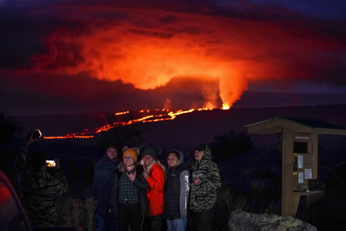 People pose for a photo in front of lava erupting from Hawaii's Mauna Loa volcano near Hilo, Hawaii, on Nov. 30, 2022. (Gregory Bull/AP Photo)