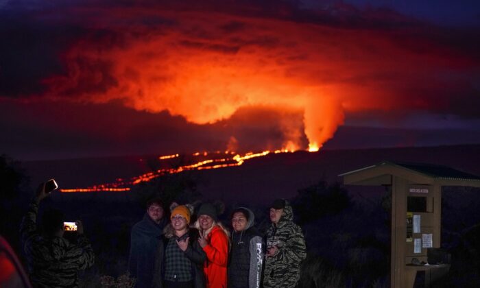 People pose for a photo in front of lava erupting from Hawaii's Mauna Loa volcano near Hilo, Hawaii, on Nov. 30, 2022. (Gregory Bull/AP Photo)
