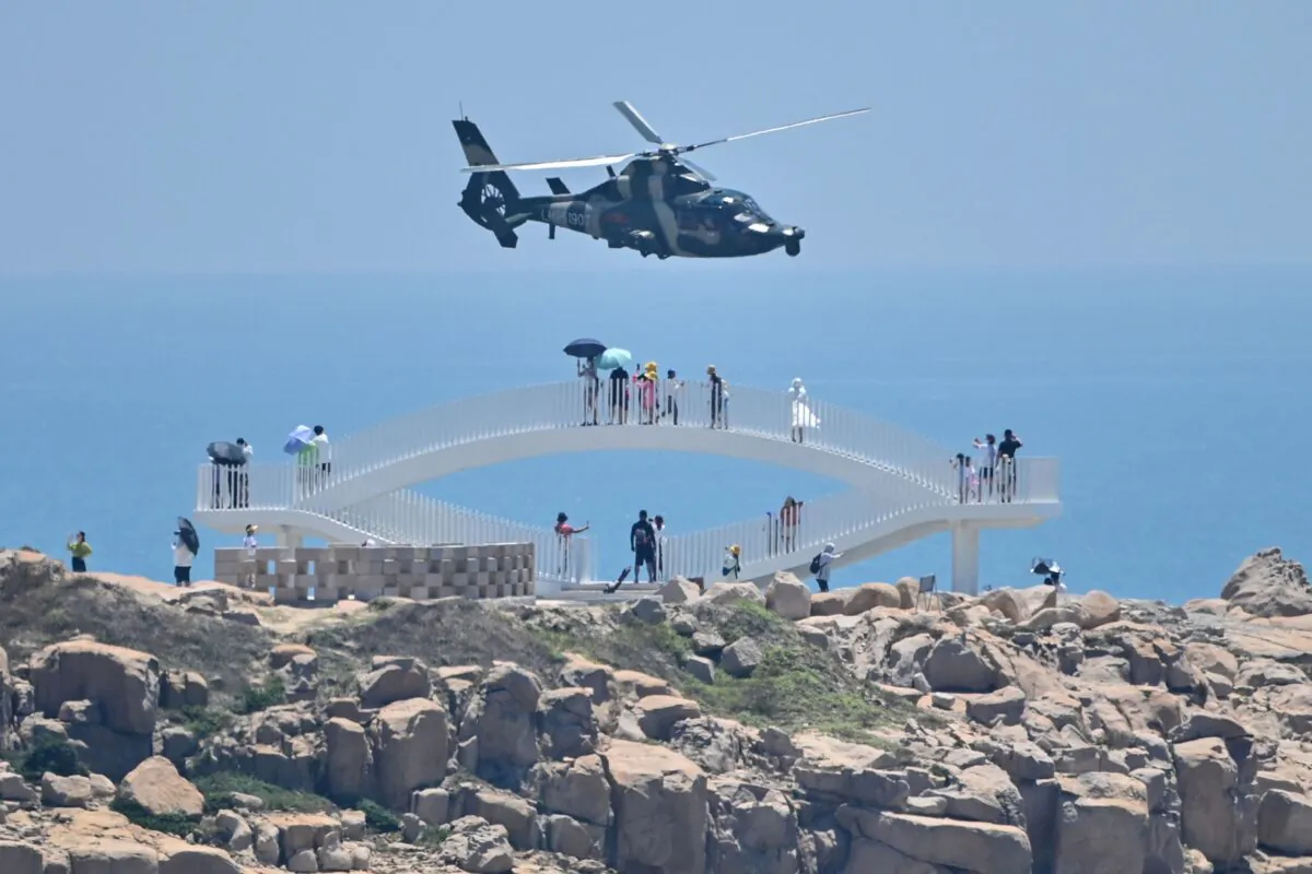 Tourists look on as a Chinese military helicopter flies past Pingtan island, one of mainland China's closest points to Taiwan, in Fujian Province, on Aug. 4, 2022. (Hector Retamal/AFP via Getty Images)