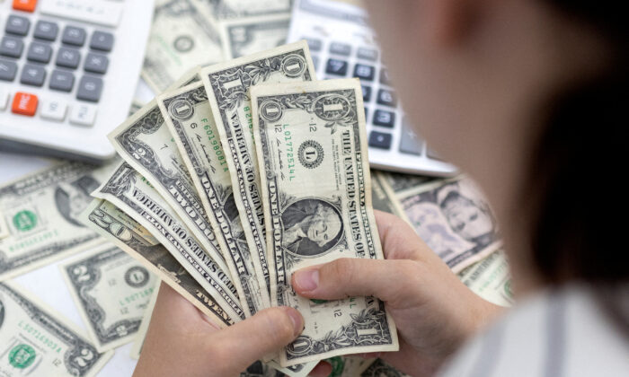 2022 年 5 月 30 日，女人拿着美元钞票。（Dado Ruvic/Illustration/Reuters）