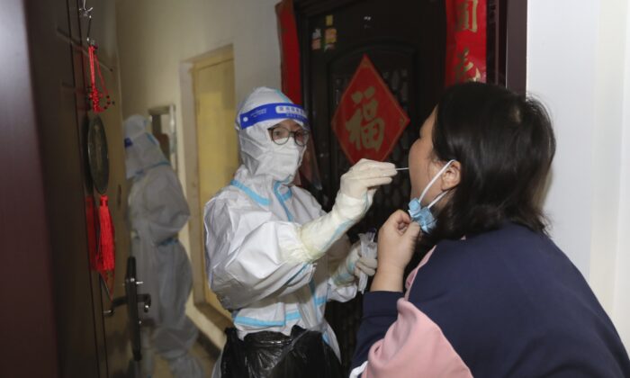 2022 年 11 月 1 日，在中国中部河南省郑州，一名医务人员在挨家挨户进行 Covid-19 筛查期间从居民身上采集拭子样本。（Chinatopix Via AP）