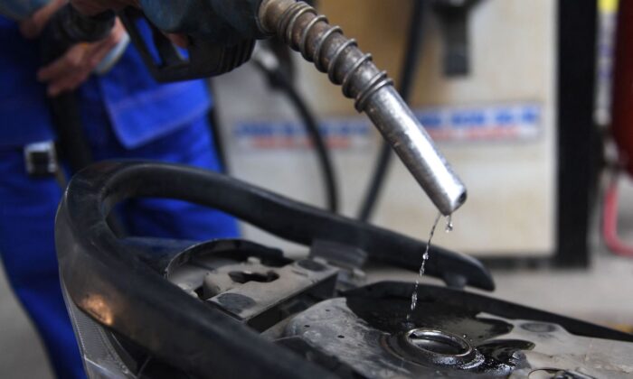 2022 年 3 月 10 日，一名加油站员工在河内将汽油泵入客户摩托车的油箱。（Nhac Nguyen/AFP via Getty Images）