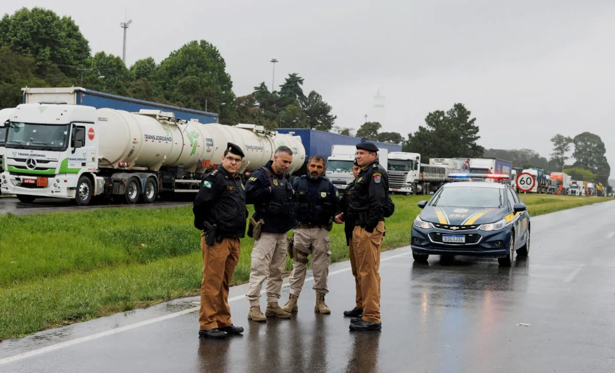 Members of the Parana State Military Police and Federal Highway Police stand on a road as supporters of Brazilian President Jair Bolsonaro block a highway during a protest over the presidential run-off election result, in Curitiba, in the state of Parana, Brazil, on Nov. 1, 2022. (Rodolfo Buhrer/Reuters)
