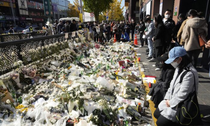 2022 年 11 月 2 日，在韩国首尔事件现场附近设立的临时鲜花铺设区，人们在周六晚上的万圣节庆祝活动中向致命的人群挤压的受害者致敬。（加拿大新闻社/美联社-安永俊)
