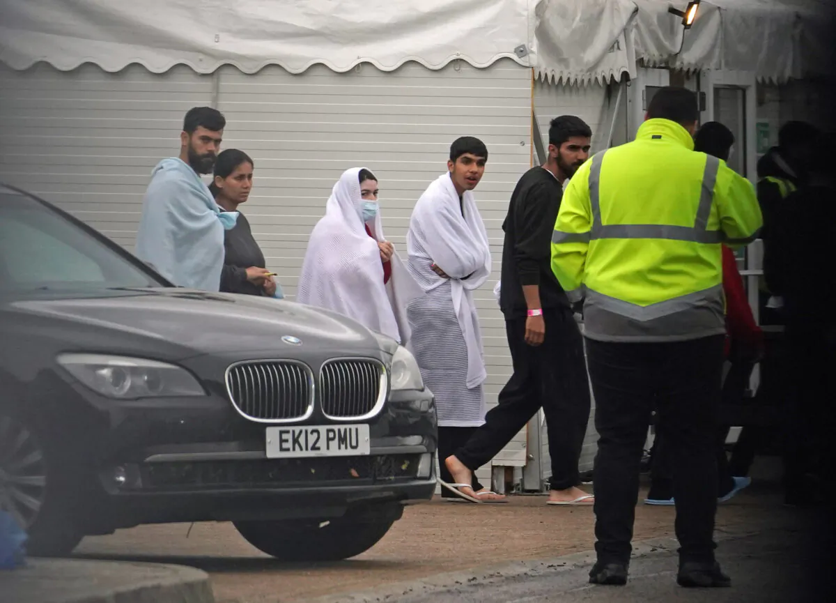 People thought to be illegal immigrants pass the car of Home Secretary Suella Braverman during her visit to the Manston migrant processing centre in Kent on Nov. 3, 2022. (PA)