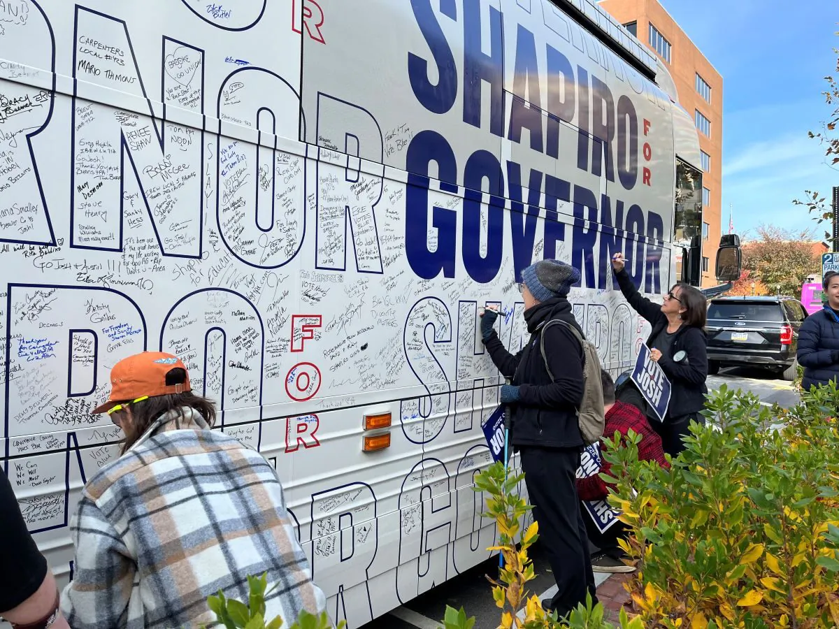 At Democrat Josh Shapiro’s bus stops, supporters are invited to write well wishes on his campaign bus. These voters sign during a Nov. 4, 2022 campaign stop in Lancaster, Pa. (Beth Brelje/The Epoch Times)