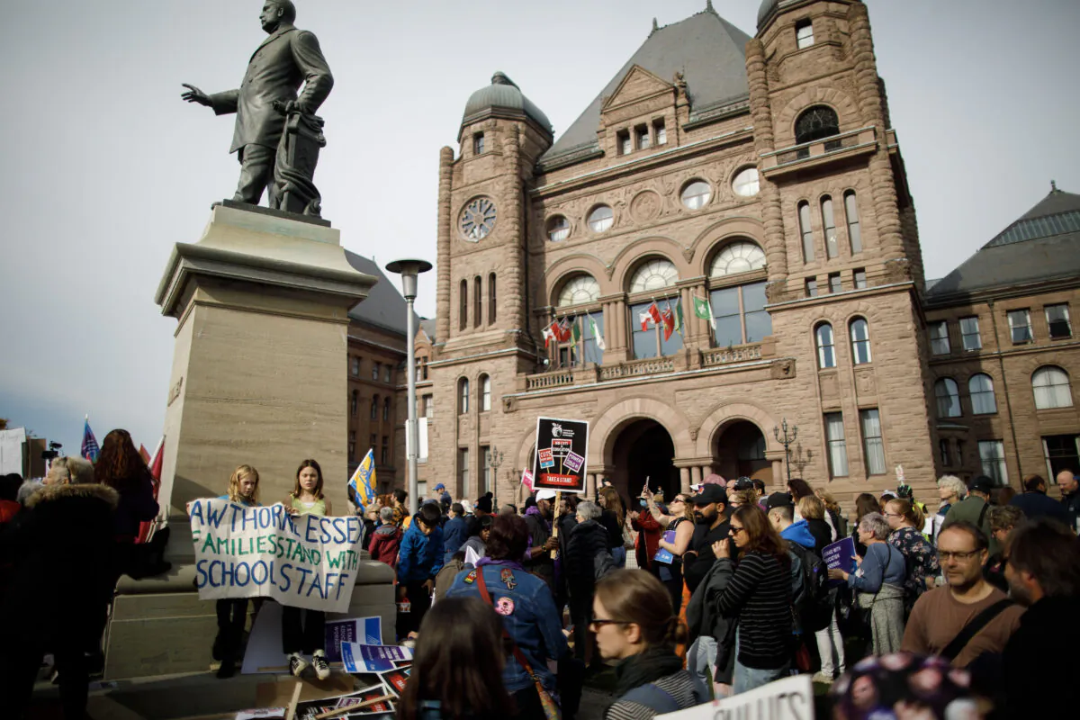 CUPE Ontario members and supporters wave signs and flags as they demonstrate outside the Queen's Park Legislative Building in Toronto on Nov. 4, 2022. (The Canadian Press/Cole Burston)
