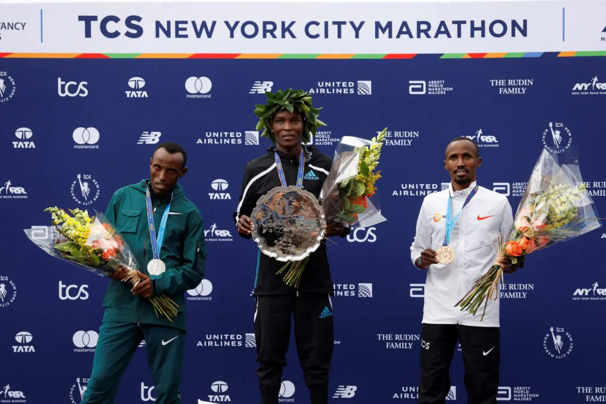 (L–R) Men's division second place finisher Shura Kitata of Ethiopia, winner Evans Chebet of Kenya, and third place finisher Abdi Nageeye of the Netherlands pose during a ceremony at the finish line of the New York City Marathon in New York on Nov. 6, 2022. (Jason DeCrow/AP Photo)