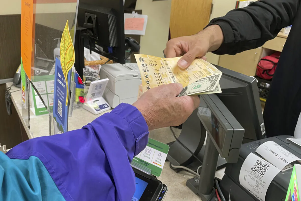 Djuan Davis hands Powerball tickets to Arpad Jakab, a retired utility worker who said it's his first time buying them, from behind the lottery counter at a Pick 'n Save store in Madison, Wis.. (Harm Venhuizen/AP Photo)