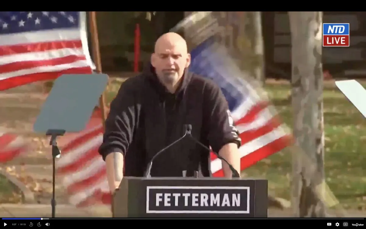 A sudden gust of wind knocked over the U.S. flags behind Senate candidate John Fetterman, as he was speaking at a rally in Pennsylvania on Nov. 5. (Screenshot via NTD)