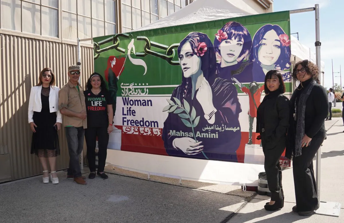 Event organizers Andisheh Tadayyon (L), Shoja Adel (2nd L), Sudi Farokhnia (3rd L), art director Hanieh Bagher (2nd R), and artist Shirin Daggooghi (R) at the "Woman, Life, Freedom" art exhibit at the Holiday Faire at Great Park in Irvine, Calif., on Nov. 5, 2022. (Rudy Blalock/The Epoch Times)