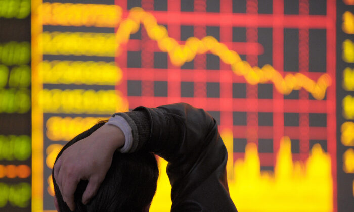 2008 年 3 月 18 日，在中国西南省份四川省成都，一名男子看着显示股价指数下降图的电子板。（刘进/法新社通过 Getty Images）