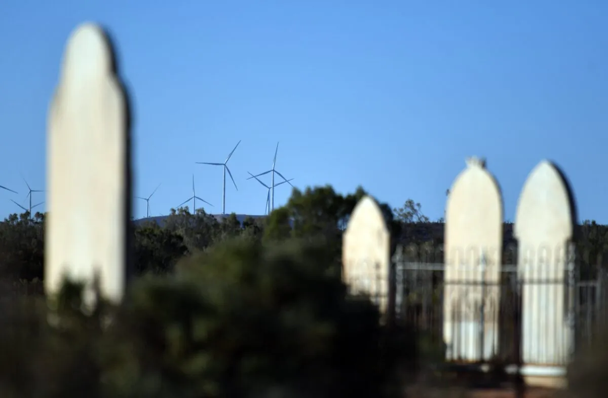 Wind turbines from the Silverton Wind Farm are seen through the tombstones of the historical cemetery in the west New South Wales town of Silverton in Australia on July 7, 2018. (AAP Image/Mick Tsikas) 