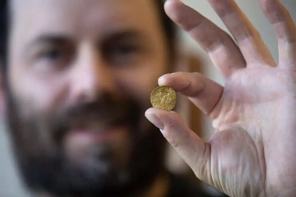 Jamie Brake, Newfoundland and Labrador provincial archeologist, displays a thin English coin at the Confederation Building in St. John's on Nov. 9, 2022. (The Canadian Press/Paul Daly)