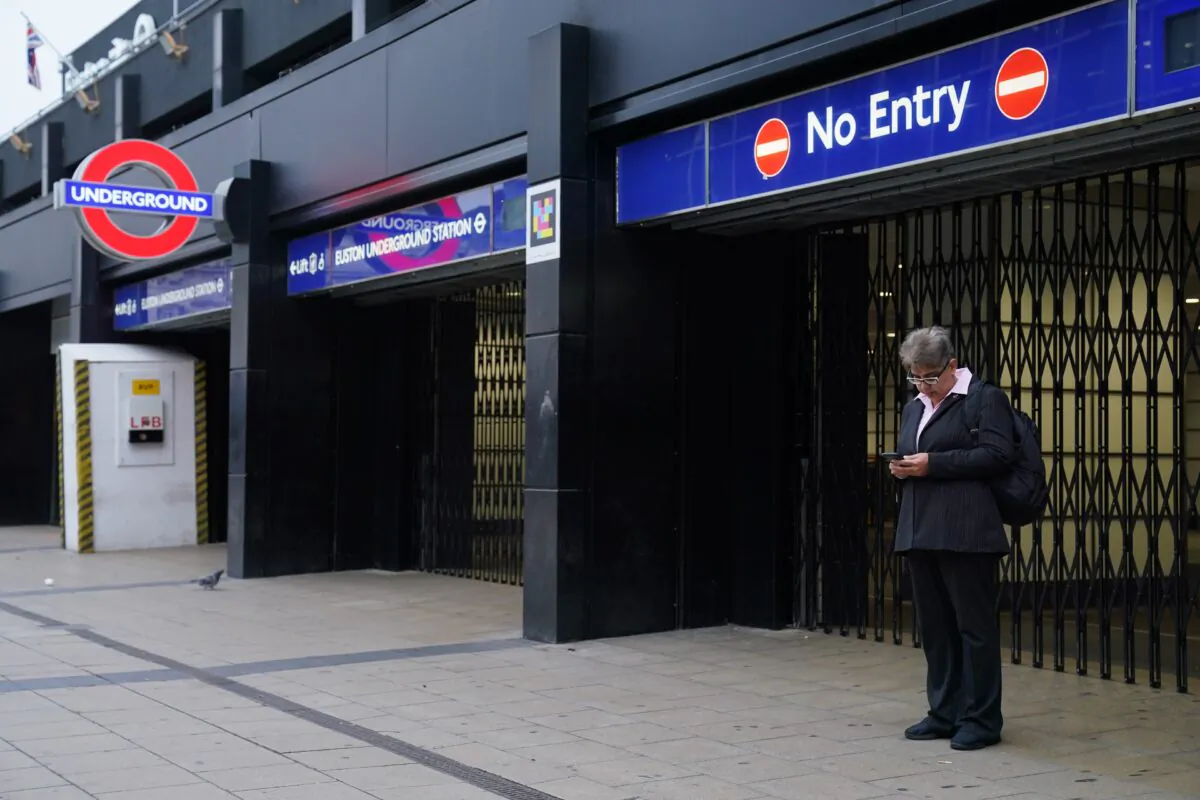 A commuter stands by the closed shutters at the entrance to Euston underground station in central London, on Nov. 10, 2022. (PA Media/Jonathan Brady)