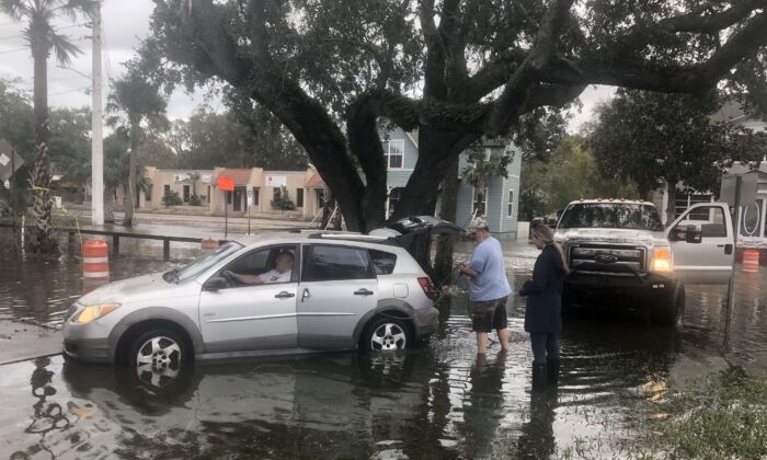 随着佛罗里达州圣奥古斯丁一条街道上的洪水迅速退去，路人托德·舒尔茨 (Todd Schultz) 努力将一辆陌生人的轿车从半小时前被咖啡色水淹没的混凝土平台上移走。  （纳内特霍尔特/媒体） 