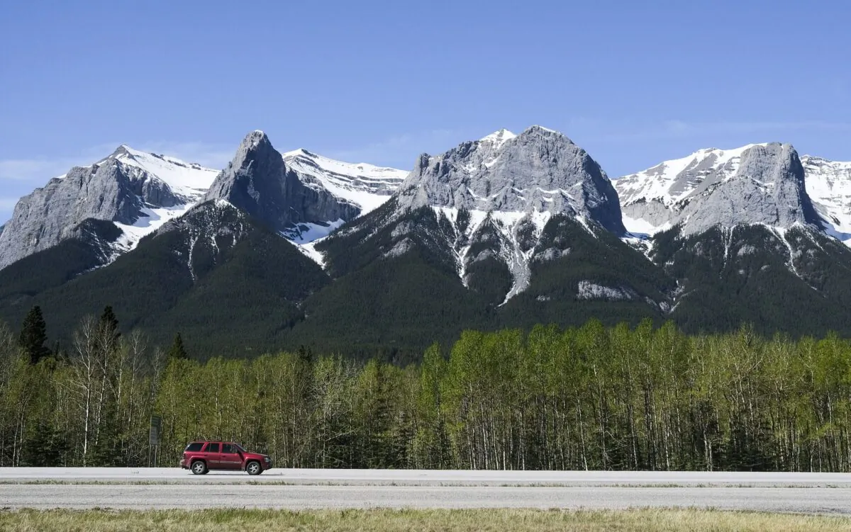 A vehicle on the Trans-Canada Highway passing through Canmore, Alta., with the Rocky Mountains in the background, on May 30, 2021. (The Canadian Press/Jeff McIntosh)