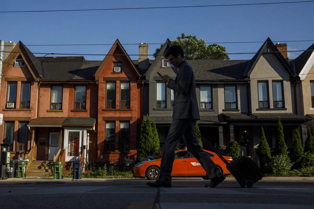 A person walks by a row of houses in Toronto on July 12, 2022. (Cole Burston/The Canadian Press)