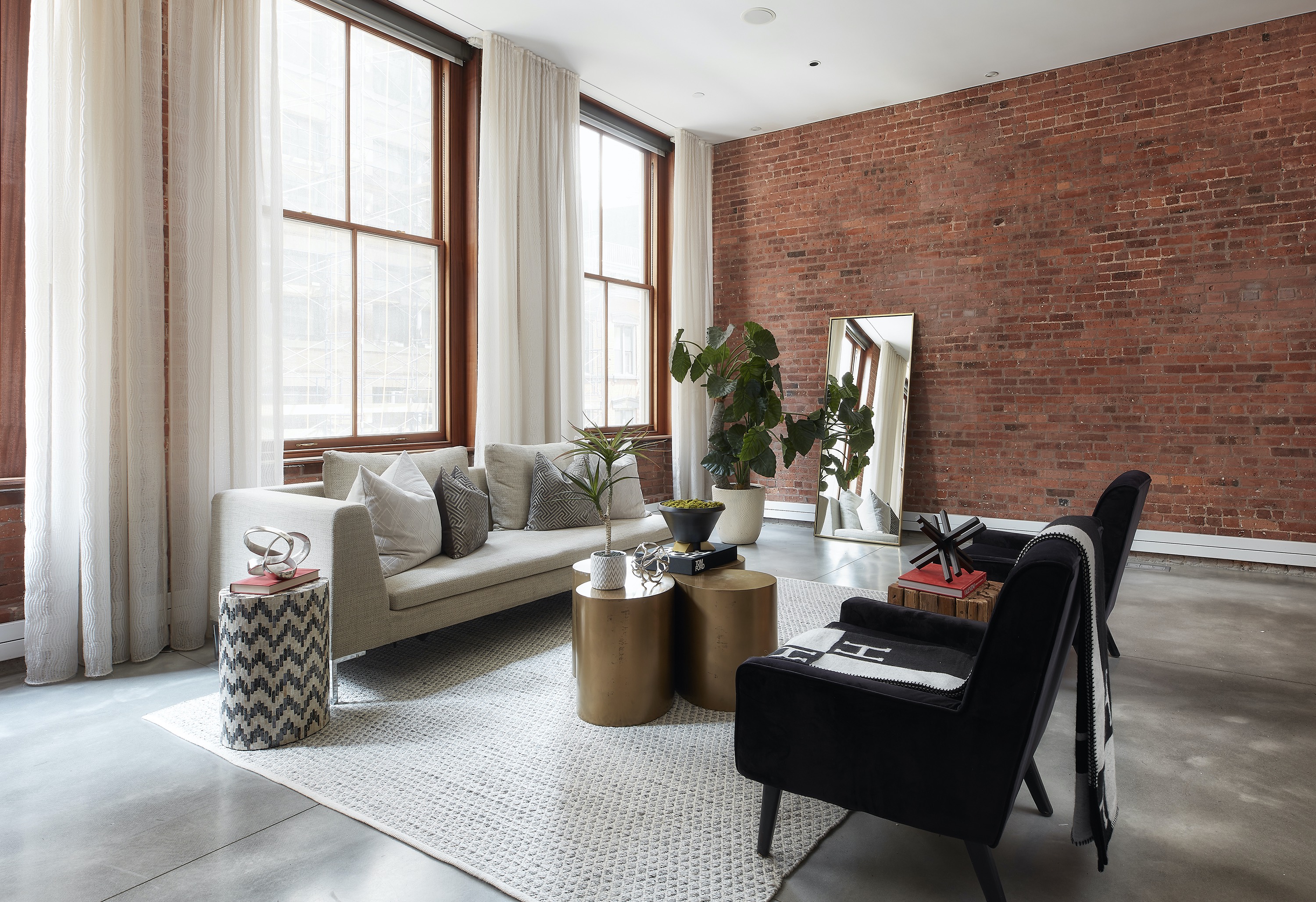 Black upholstered furniture is paired with gold accent tables and accessories in this loft living space.