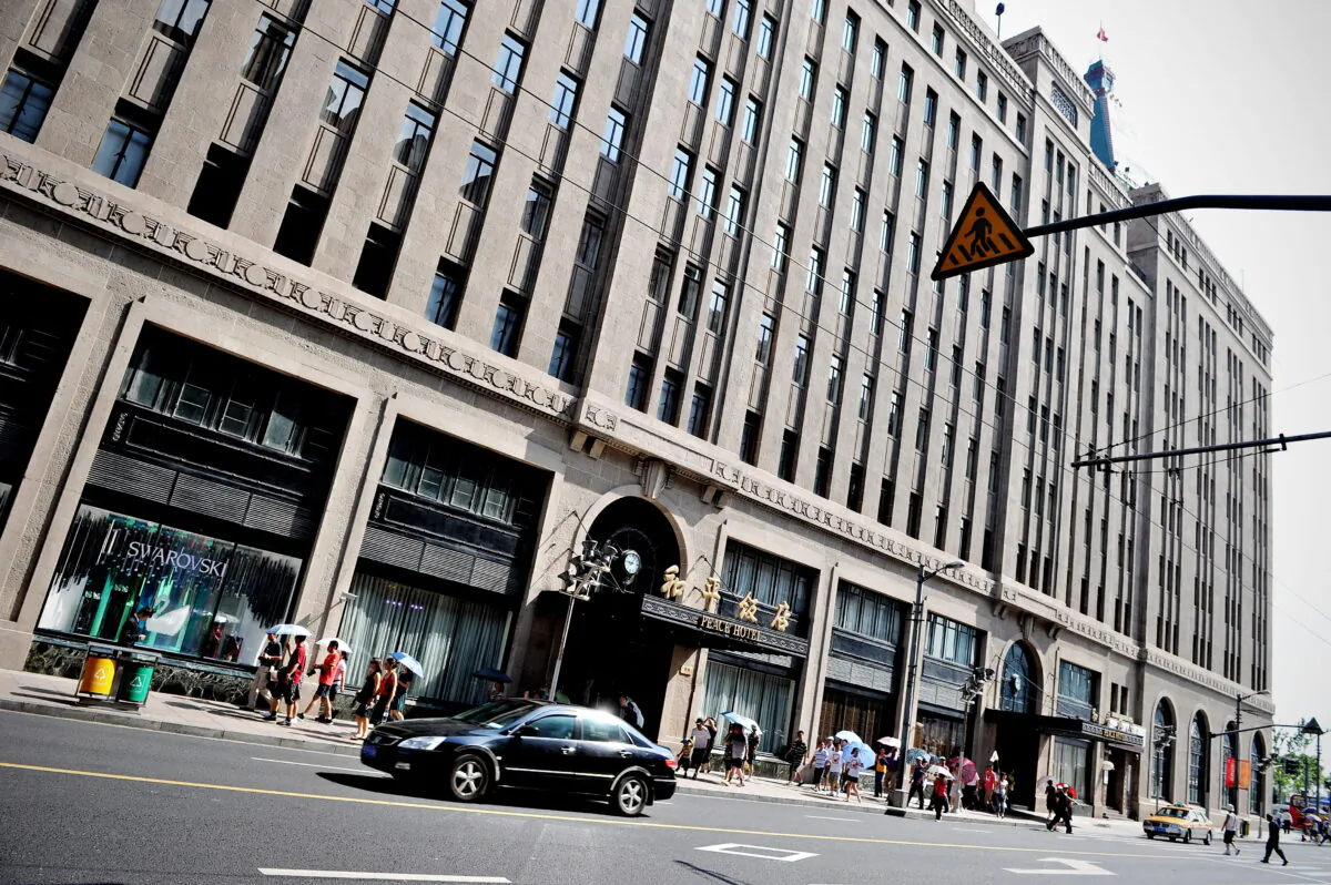 Pedestrians walk past the Peace Hotel in Shanghai on July 28, 2010. (Philippe Lopez/AFP via Getty Images)