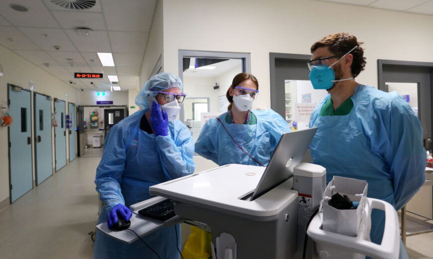 India Wells、RN 和急诊科 OPNUM、RN Danielle Callaghan 和 RN James Shattock 于 2021 年 12 月 4 日在澳大利亚悉尼圣文森特医院急诊科就 COVID-19 红区的患者转移进行咨询。（Lisa Maree Williams /盖蒂图片社）
