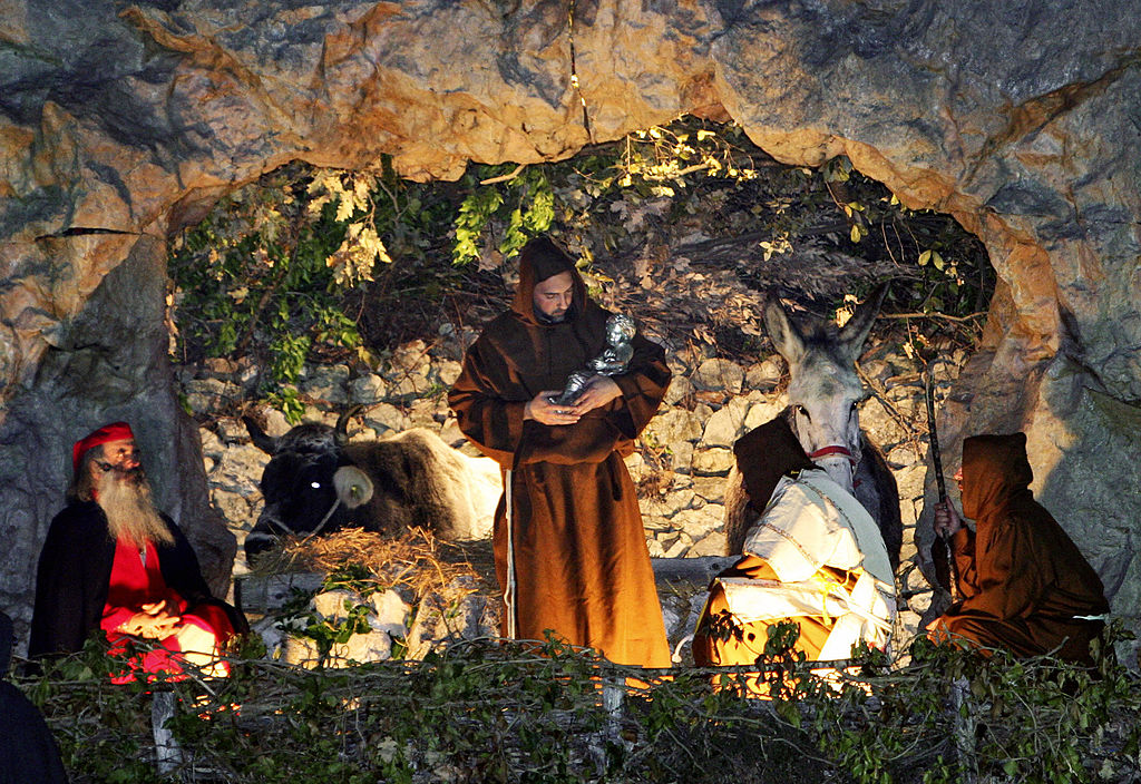 2007 年 12 月 24 日，一名 Greccio 市民打扮成圣弗朗西斯，在意大利中心村庄重建 1223 年由意大利圣徒制作的第一个耶稣诞生。（Paolo Tosti/AFP via Getty Images）