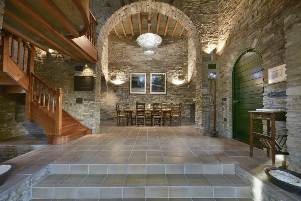 The main residence features a formal dining area, with a sitting area located on the mezzanine level, all accented by natural stone. (Courtesy of Greece Sotheby’s International Realty)