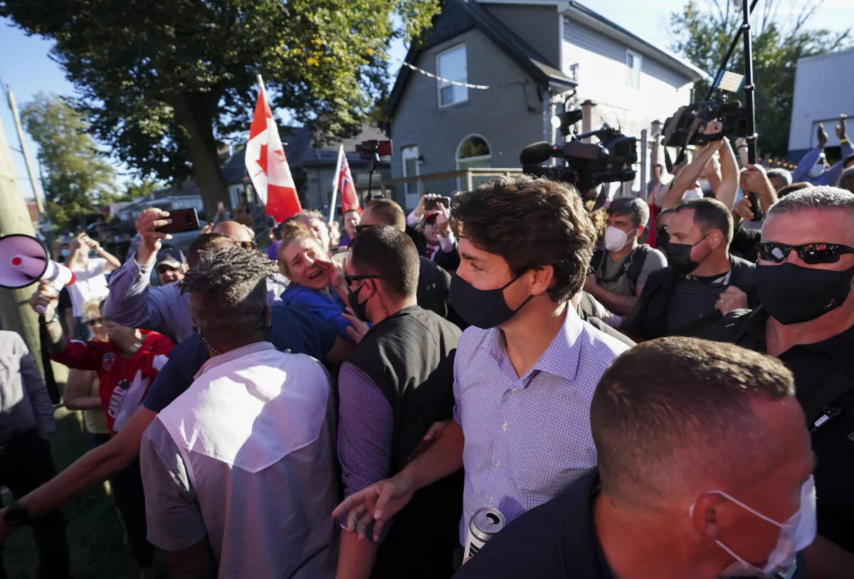Liberal Leader Justin Trudeau is escorted by his RCMP security detail as protesters shout and throw gravel while leaving a campaign stop at a local micro brewery during the Canadian federal election campaign in London, Ont., on Sept. 6, 2021. (Nathan Denette/The Canadian Press)