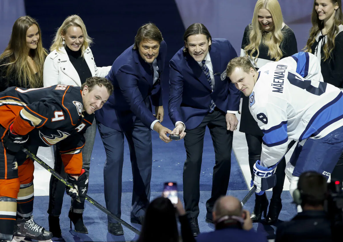 Former Winnipeg Jets' Teppo Numminen, center right, and Teemu Selanne, center left, prepare to drop the puck during a ceremony where they were inducted into the Winnipeg Jets Hall of Fame prior to an NHL game against the Anaheim Ducks in Winnipeg, Manitoba, on Nov. 17, 2022. (John Woods/The Canadian Press via AP)