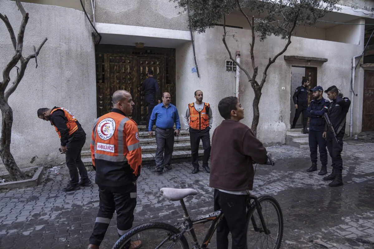 Members of the police and civil defense stand in front of a three story building where a deadly fire broke out in the Jebaliya refugee camp, killing 21 members of the Palestinian Abu Raya family in the northern Gaza Strip, on Nov. 18, 2022. (Fatima Shbair/AP Photo)