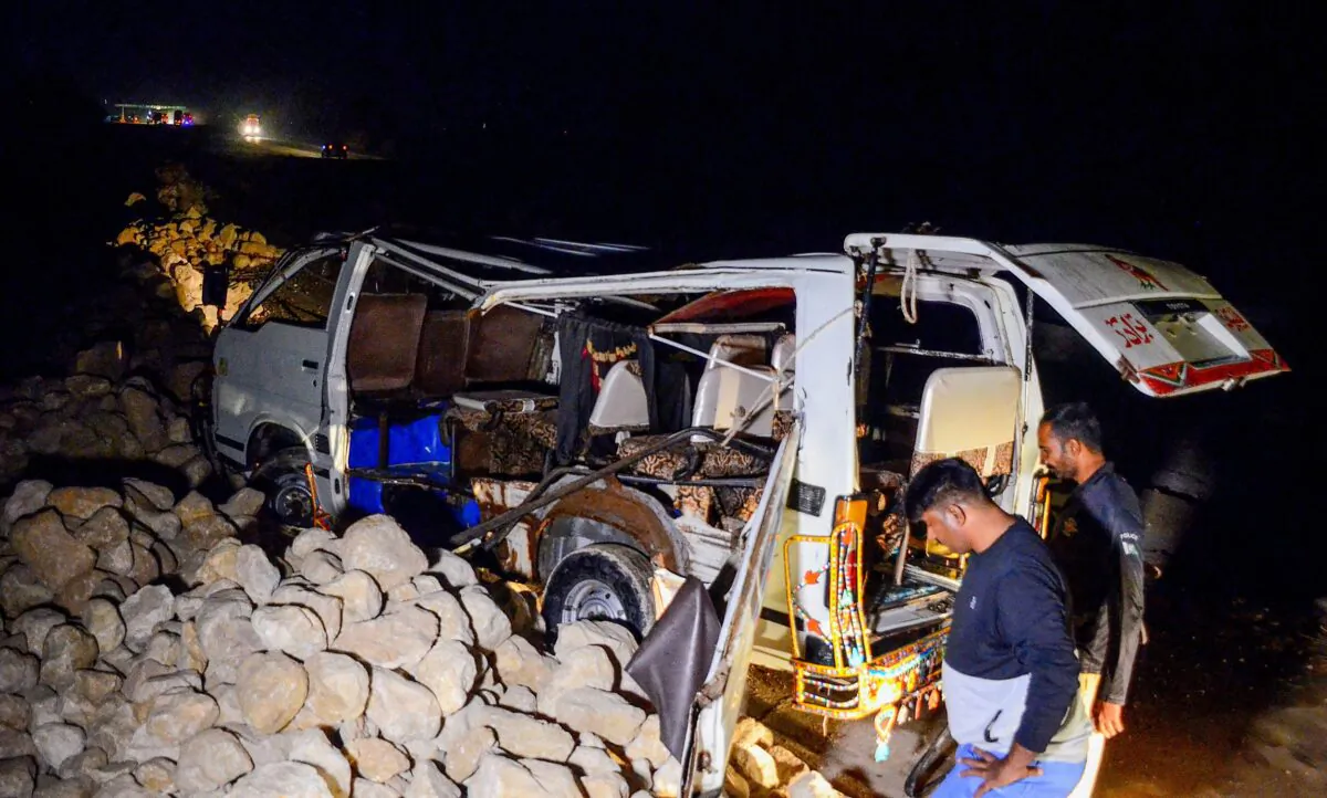 A policeman stands beside a damaged passenger mini bus after an overnight accident in Sehwan of Sindh Province on Nov. 18, 2022. (Husnain Ali/AFP via Getty Images)
