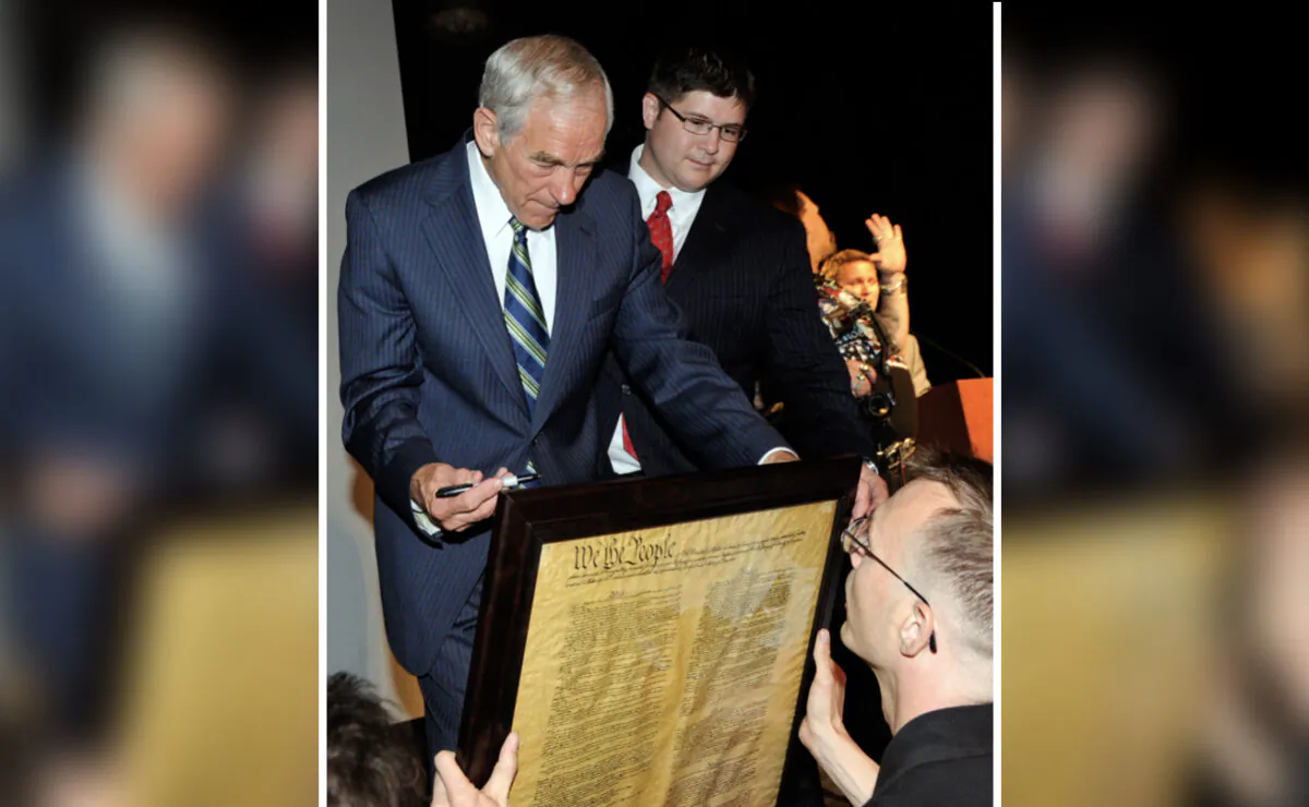 File photo showing then-Rep. Ron Paul (R-Texas) signing a copy of the U.S. Constitution for a supporter as Paul’s then-campaign manager Jesse Benton (C) looks on, at an event in Las Vegas, Nev., on May 17, 2011. (Ethan Miller/Getty Images)