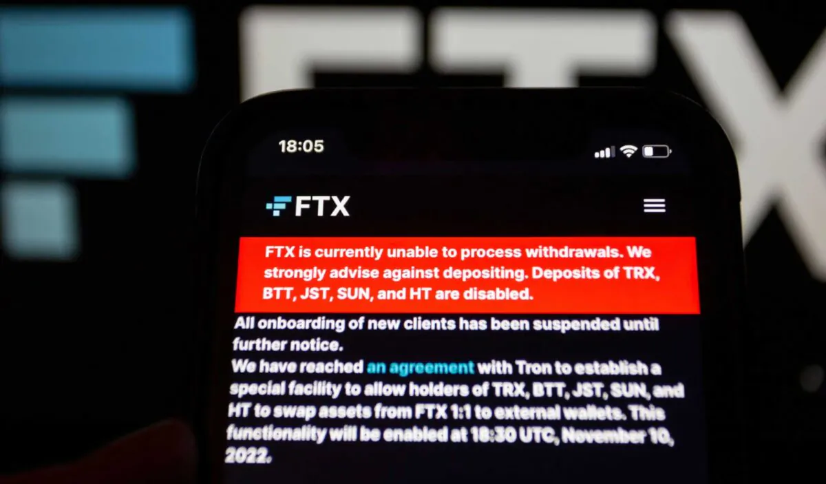 A man holds an iPhone XR on which is a message from crypto exchange FTX that payouts have been stopped due to insolvency, in Munich, Germany, on Nov. 12, 2022. (Rcc_Btn/Shutterstock)
