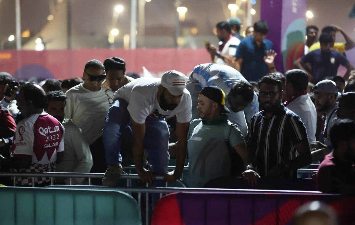 Fans jump over barriers at a fan festival before the opening World Cup match between host Qatar and Ecuador at Al Bidda Park in Doha, Qatar, on Nov. 20, 2022. (Carl Recine/Reuters)