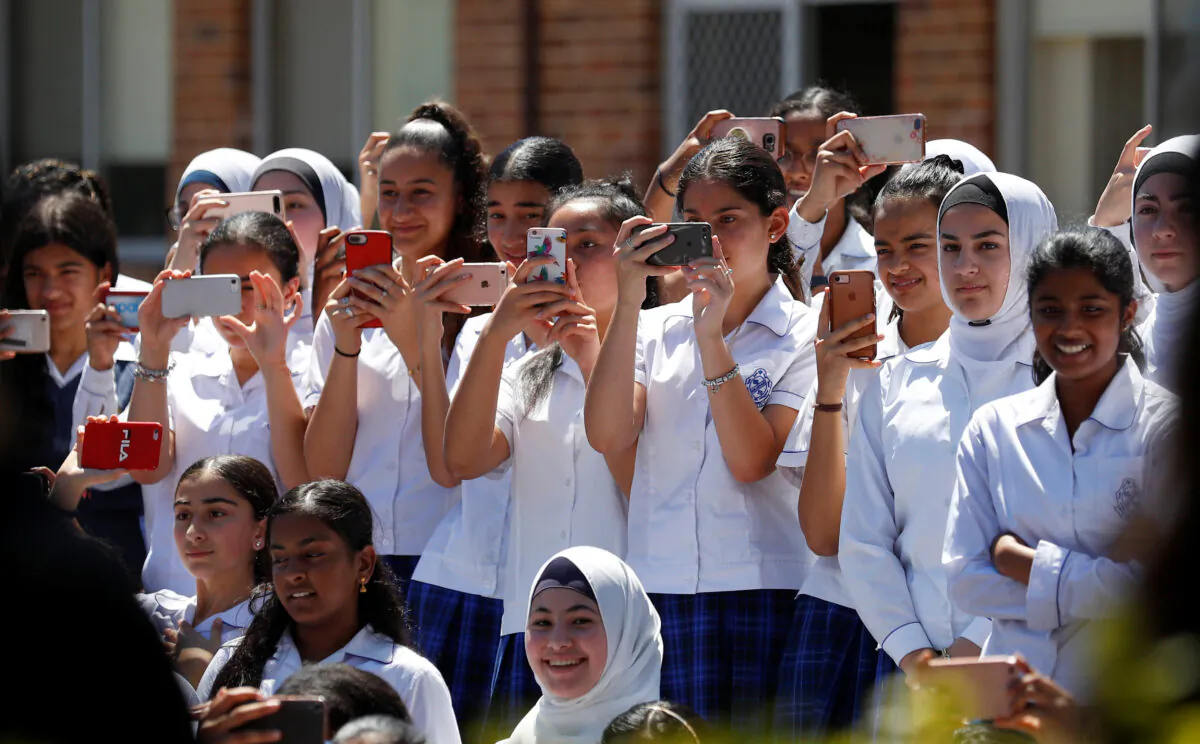 Schoolgirls wait with their mobile phones up for the arrival of Prince Harry, Duke of Sussex and Meghan, Duchess of Sussex at Macarthur Girls High School in Sydney, Australia, on Oct. 19, 2018. (Phil Noble - Pool/Getty Images)
