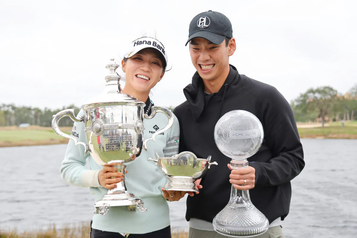 Lydia Ko of New Zealand poses for a photo with her fiancé, the Vare Trophy, the Rolex Player of the Year trophy and the CME Globe trophy after winning the CME Group Tour Championship at Tiburon Golf Club in Naples, Flor., on Nov. 20, 2022. (Michael Reaves/Getty Images)