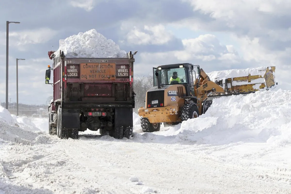 Crews truck snow in to dump in the parking lot of Erie Community College in Orchard Park in Erie County, N.Y., on Nov. 20, 2022. (Mark Mulville/The Buffalo News via AP)