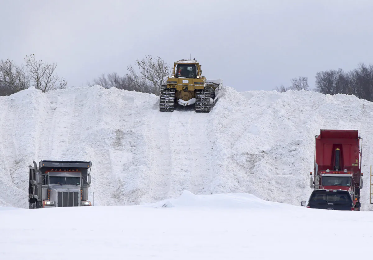 Crews truck snow in to dump in the parking lot of Erie Community College in Orchard Park, N.Y., on Nov. 20, 2022. (Mark Mulville/The Buffalo News via AP)