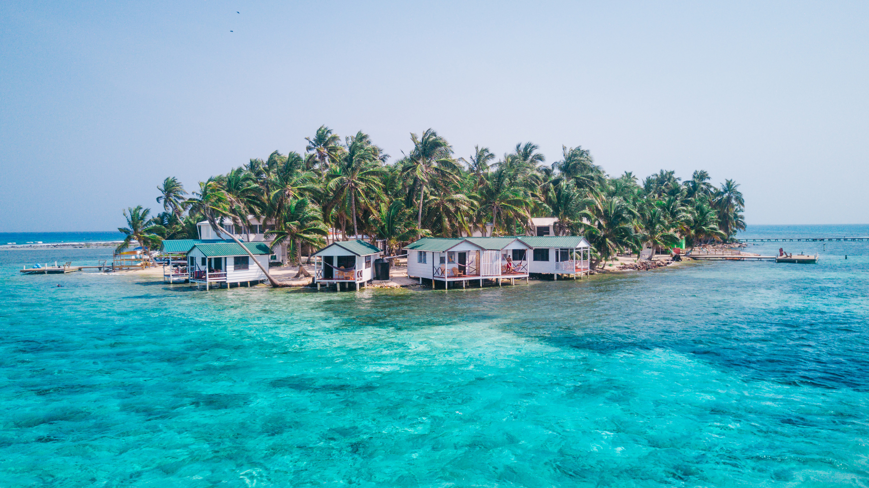 Tobacco Caye small Caribbean island with palm trees and bungalows in the Belize Barrier Reef.